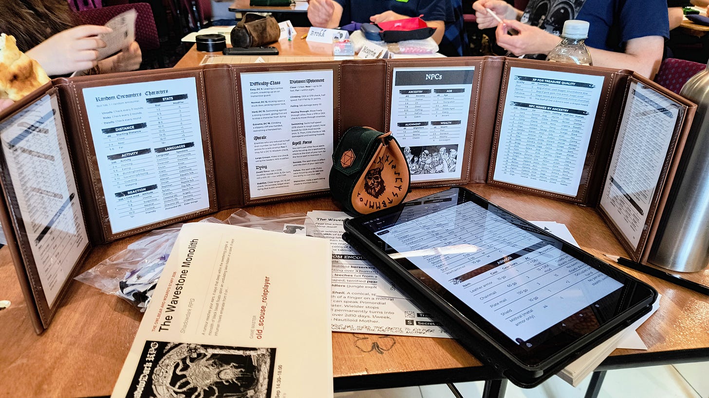 A table with a GM screen, dice bag, cardboard minis and game notes A table with a GM screen, dice bag, cardboard minis and game notes