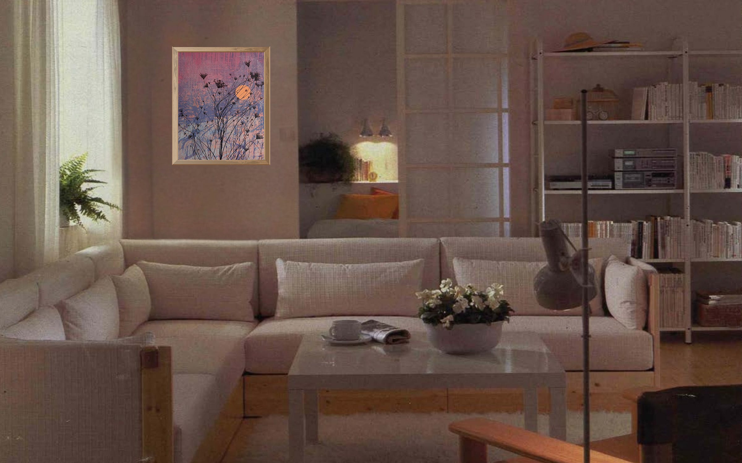 A pale 1985 catalog living room with a cream sectional sofa and white bookshelves, and a framed painting of dark grasses against a pink and violet sky on the wall.