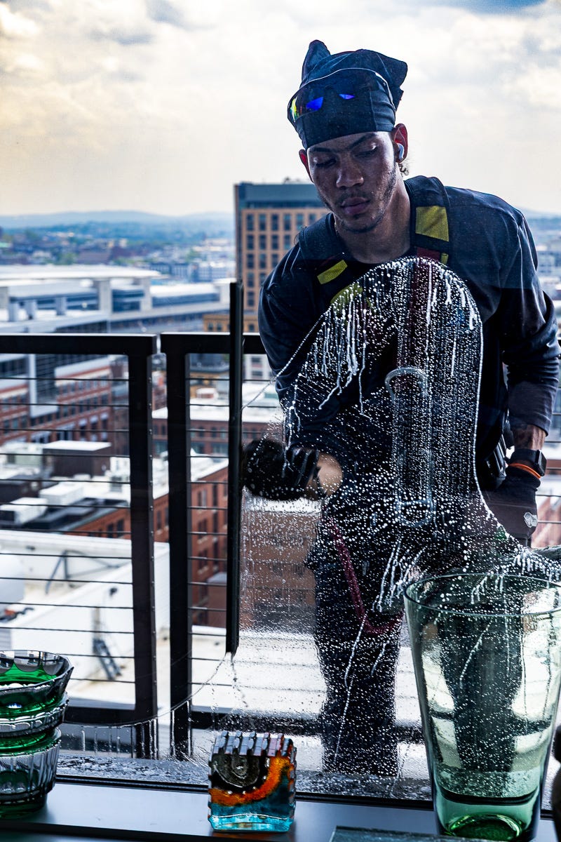 Window washer holding squeegee in hand mid-clean, with strong visual clarity.