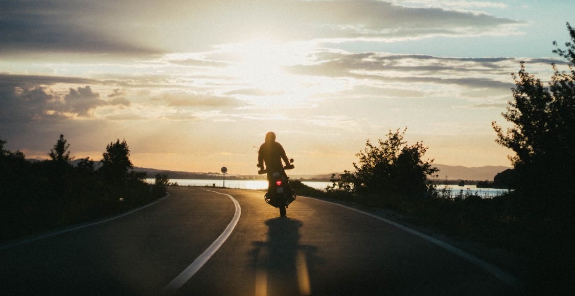 Free Silhouette of a motorcyclist riding on a scenic road during a beautiful sunset, emphasizing freedom and adventure. Stock Photo Free Silhouette of a motorcyclist riding on a scenic road during a beautiful sunset, emphasizing freedom and adventure. Stock Photo