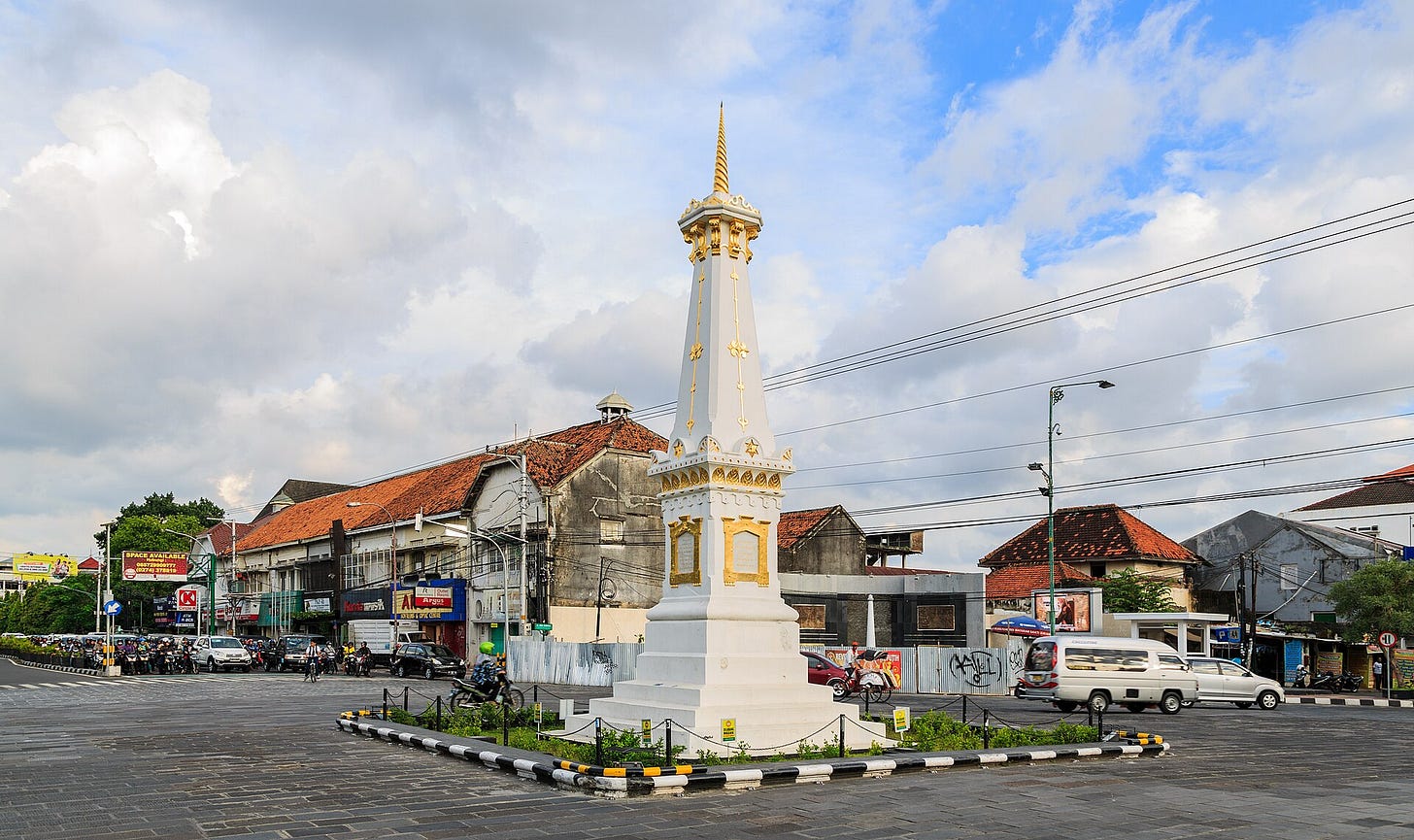 Tugu Jogja 是一座历史悠久的支柱，矗立在繁忙的十字路口，周围环绕着城市建筑。 （照片：维基共享资源） 