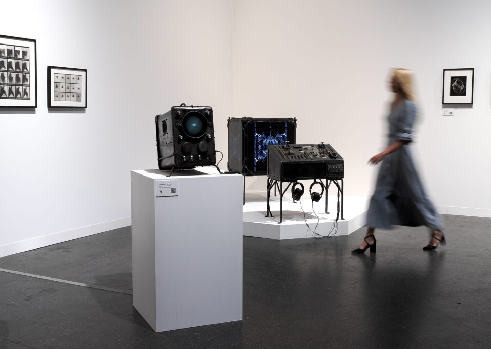 Asprey Studio’s Zero 10 booth presents 0xDEAFBEEF’s forged-iron audiovisual sculptures and framed works in a white-walled exhibition space.