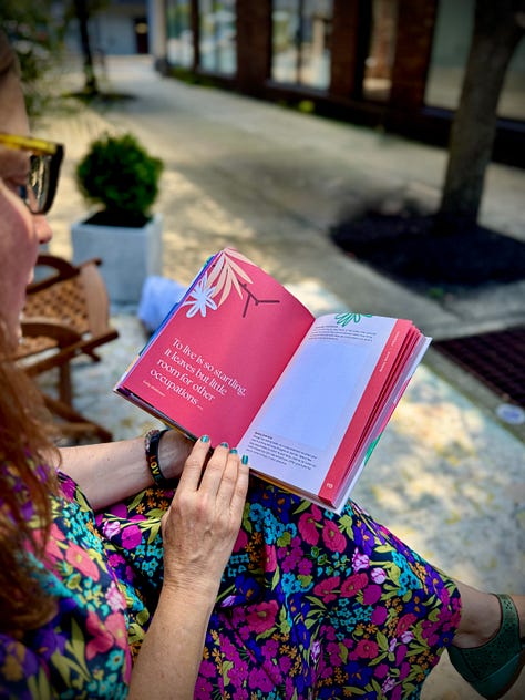 A person wearing a colorful floral dress sitting outdoors, reading an open copy of Writing With The Seasons showing an Emily Dickinson quote on a bright pink page. The back of the journal and A close-up view of a person holding open Writing With The Seasons, displaying the vibrant, leaf-patterned front and back cover.