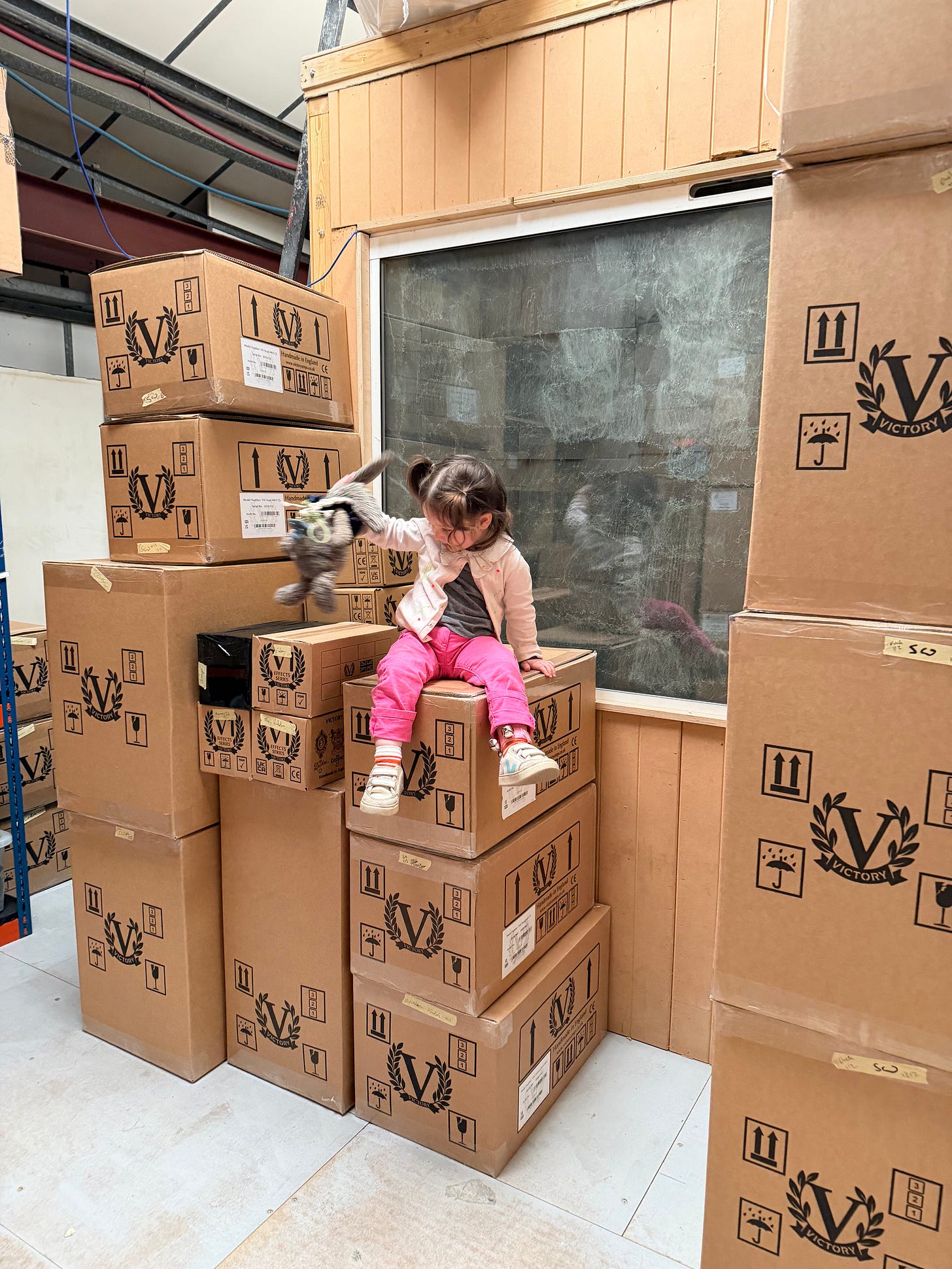 anthonys daughter holds her bunny sitting on top of the victory amp boxes in the factory in hop pink pants and a little sweater