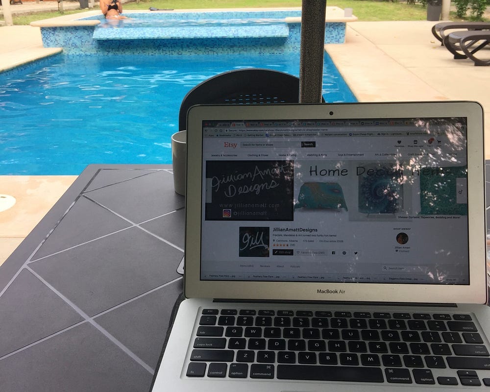 A laptop sits on a table with a pool in the background.