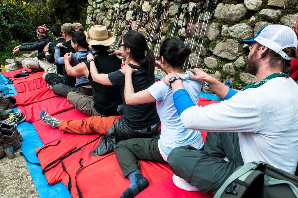 A line of people sitting and massaging each other's shoulders