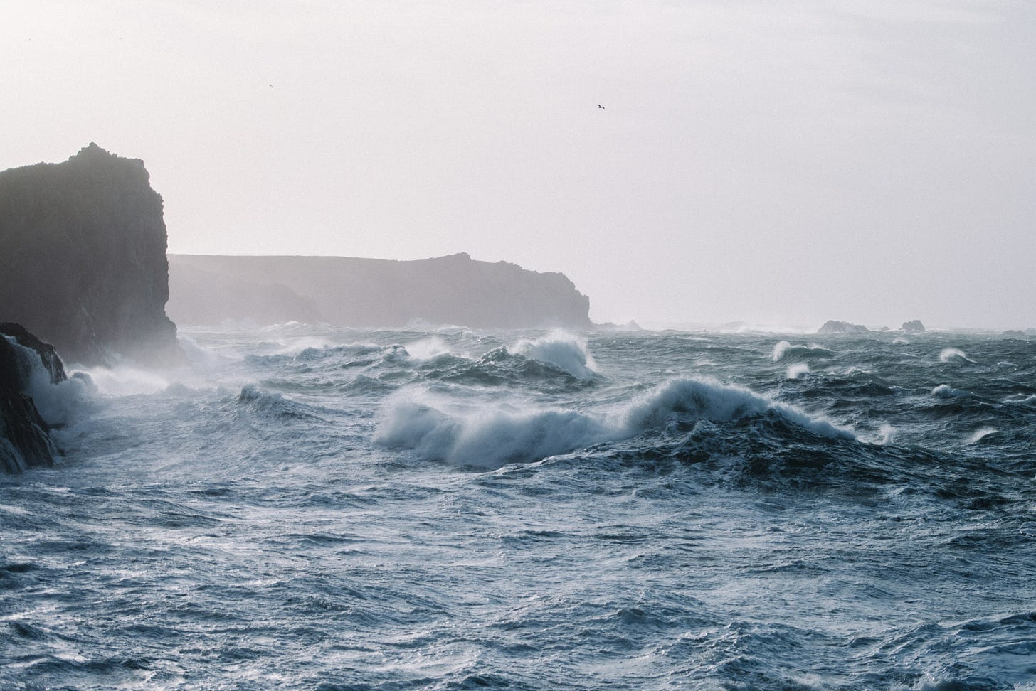 ocean waves crashing to shore with cliffs
