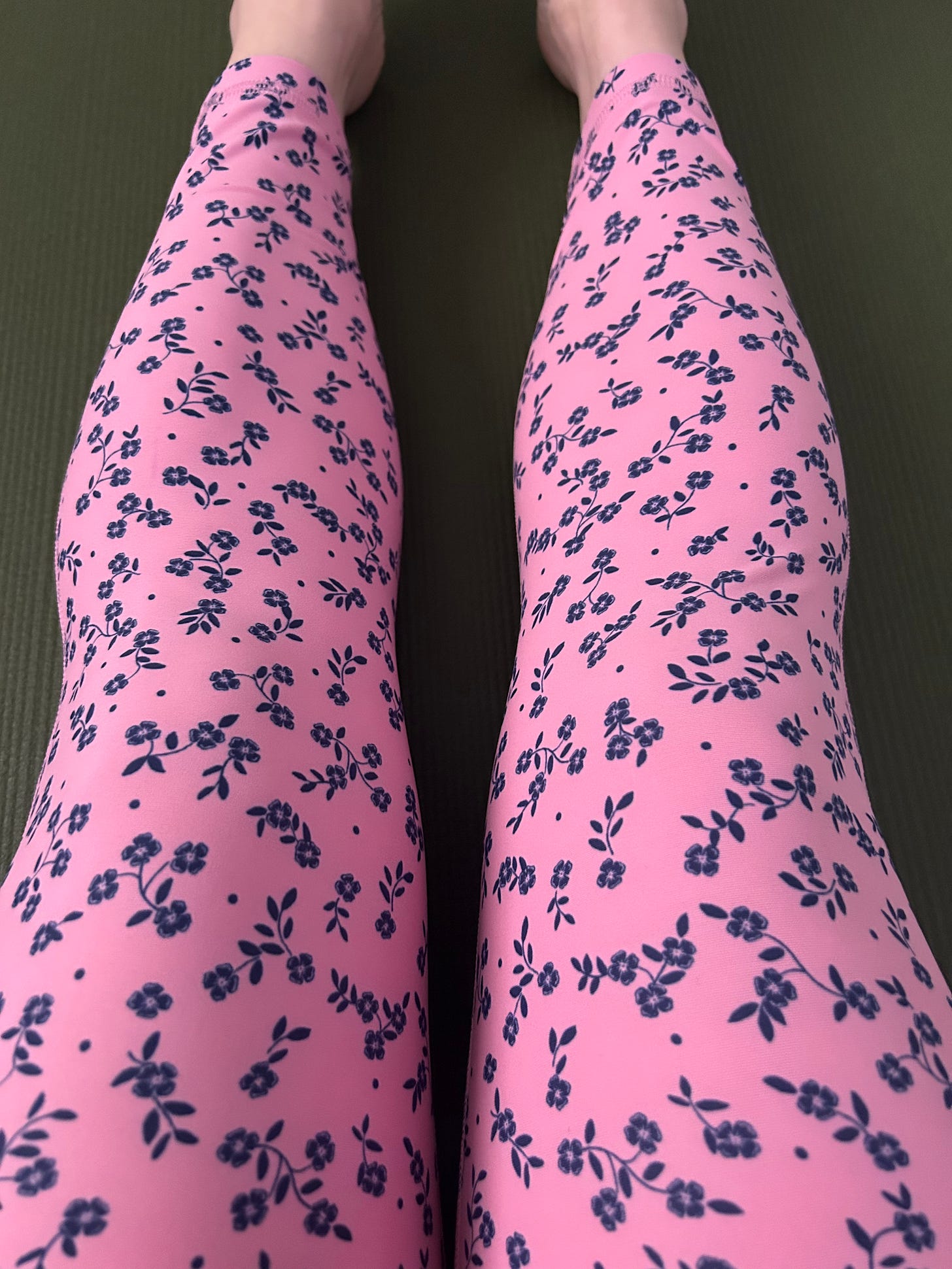 woman's legs in pink and blue floral leggings on a yoga mat