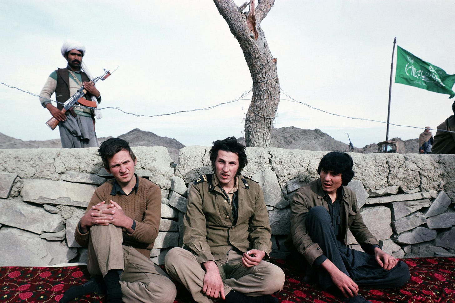 A stark image of three captive Soviet soldiers at a Mujahideen mountain camp, January 6, 1982, amidst the Soviet-Afghan War.