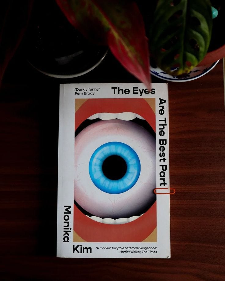 This may contain: a book with an eye on it sitting on top of a wooden table next to a potted plant