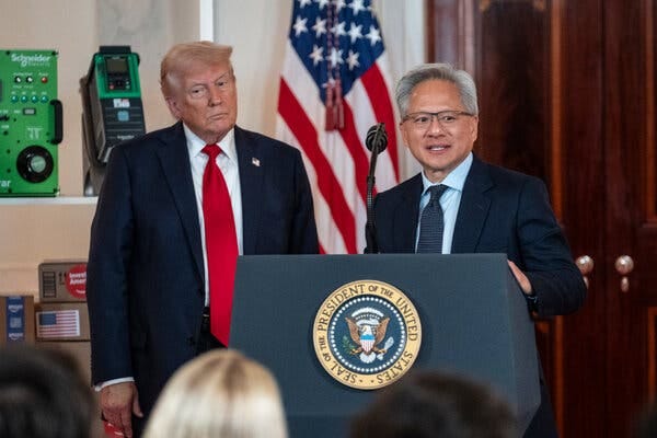 Jensen Huang speaks behind a lectern wearing a suit. Donald Trump stands behind him.