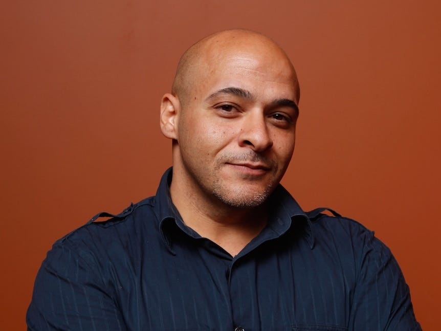 Portrait of a man smiling into the camera, while standing against an orange background Portrait of a man smiling into the camera, while standing against an orange background