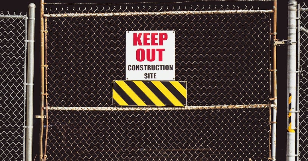 person in black shirt walking on brown sand near gray metal fence during daytime
