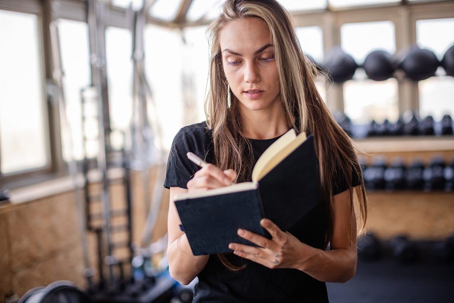 Woman writing in a journal with gym equipment in the background