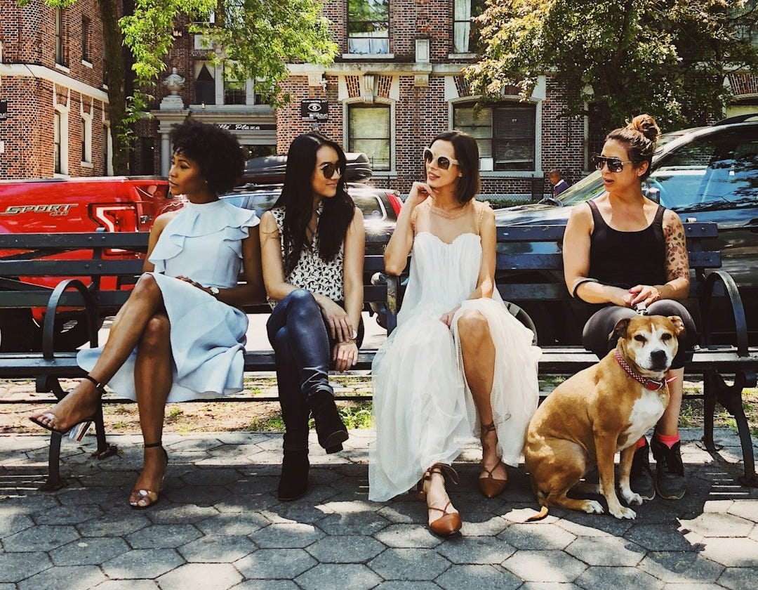 four women sitting on black steel bench during daytime