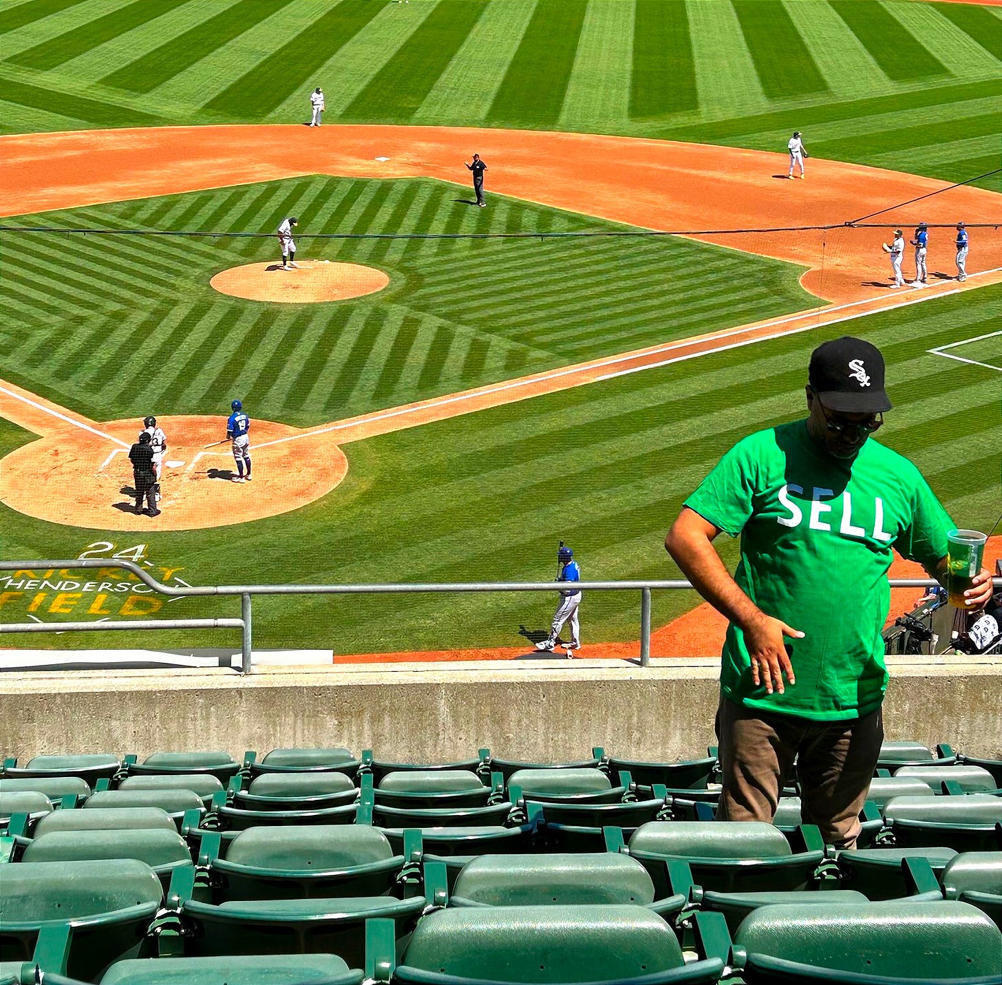 Baseball scene at Oakland Coliseum in the background, with a fan in a 'Sell' t-shirt in the foreground