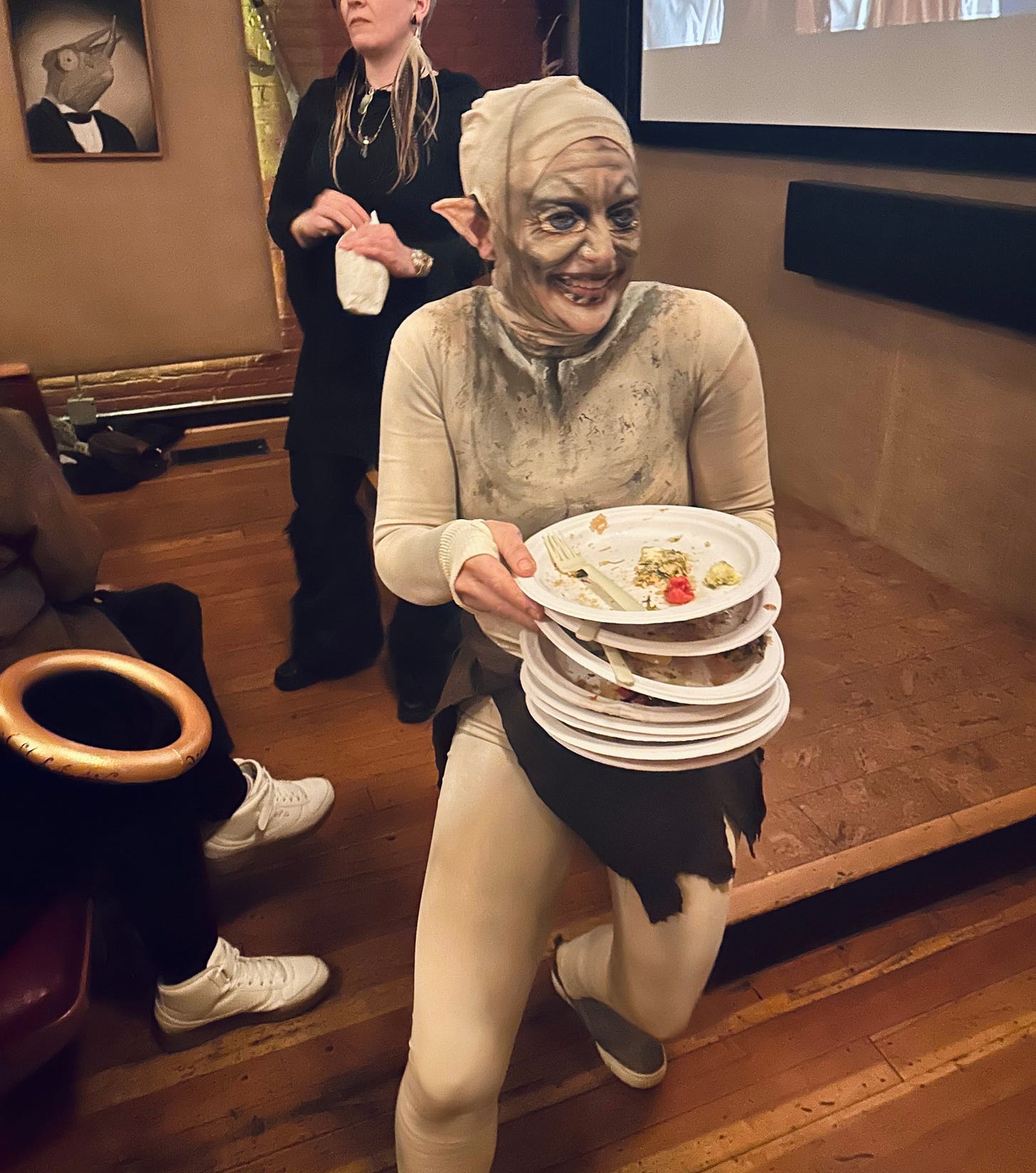 Woman dressed as Gollum with a stack of plates