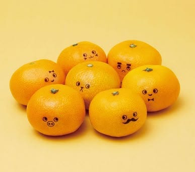This may contain: five oranges with faces drawn on them sitting in a pile together against a yellow background