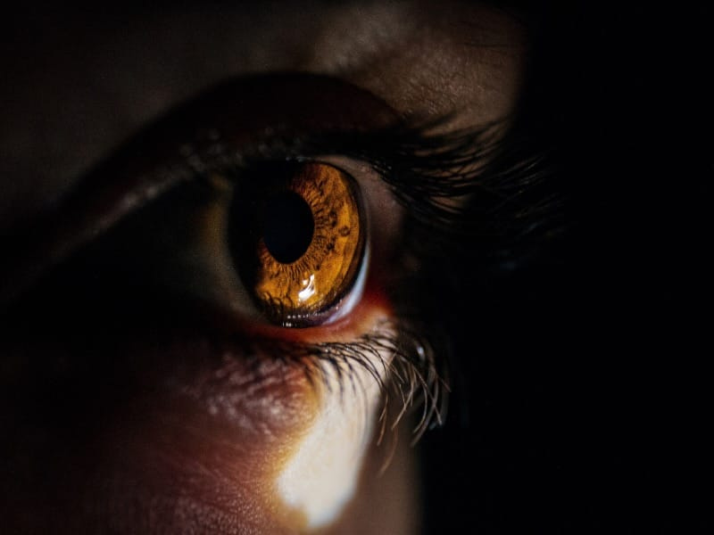 Macro closeup shot of a human eye looking to a small light from a dark room