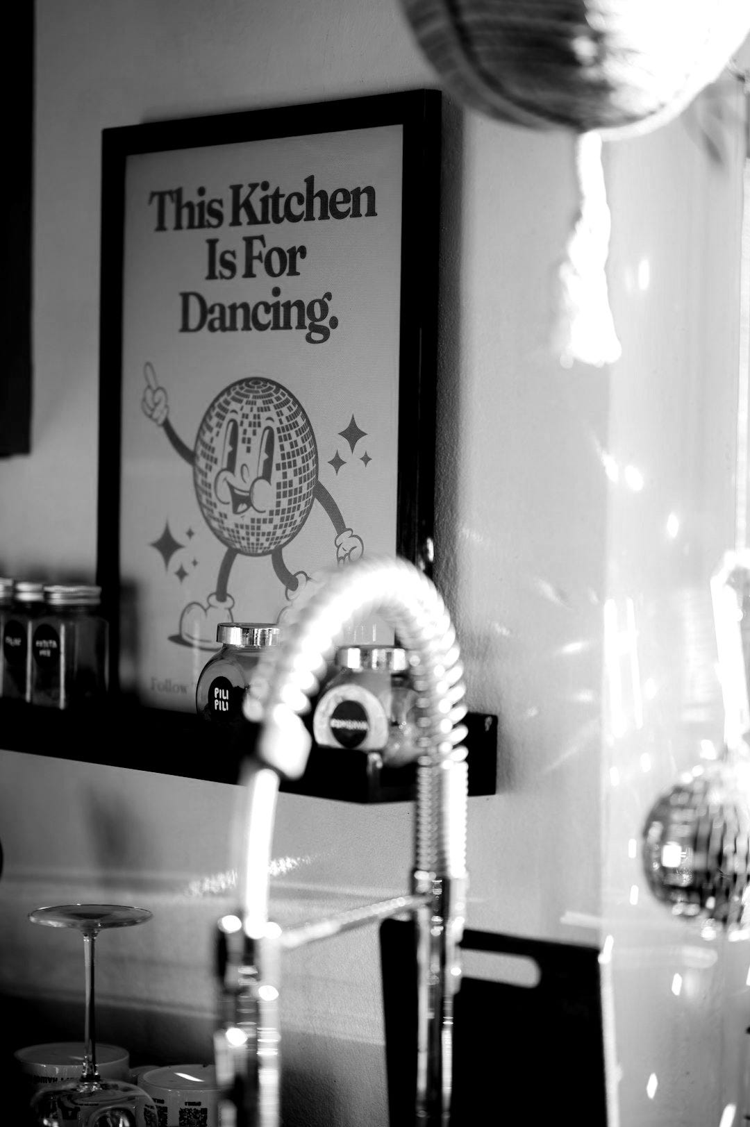 a kitchen sink with a faucet and a poster above it