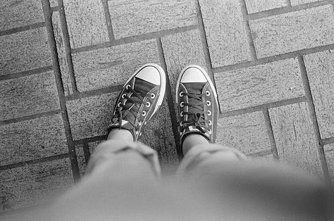 Counter-clockwise from top left: view from photographer's eye-level perspective of her feet in converse sneakers; three customers framed by two cars in adjacent parking lot at a ventanita, or coffee window, of a Cuban restaurant; portrait of young boy looking straight to camera with trees in background; image of photography lab; skyward view of sun poking through oak trees with and American flag in opposite corner; landscape view of a strip mall in suburban Miami.