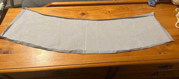 Photos of fabric lampshade pieces laid out flat. One is a solid light blue with interfacing attached to the wrong side. The other is a patchwork of blue crosses and grey squares