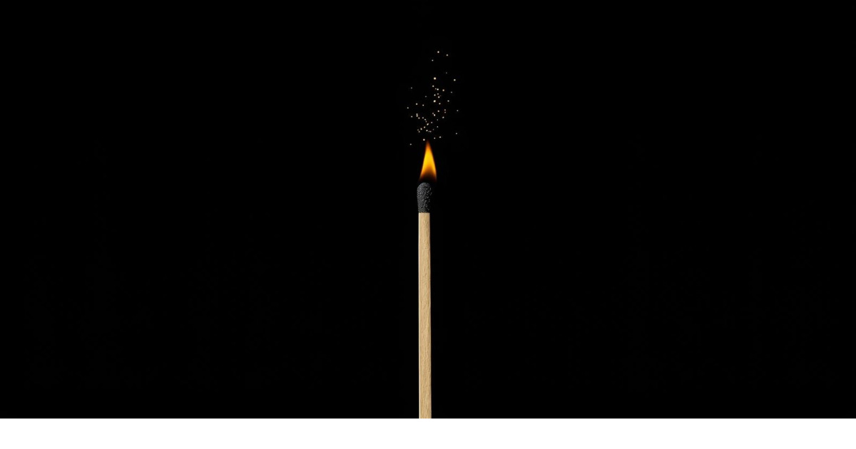 A single cream-colored matchstick rests on a dark charcoal background, its tip gently lit with a small flame — symbolizing a quiet, intentional spark of purpose.