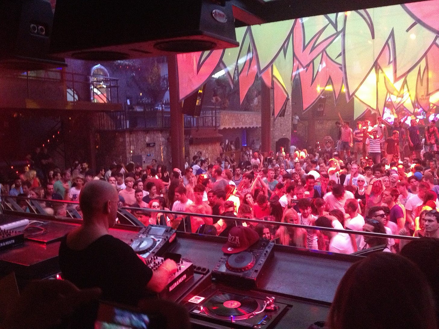 A scene of a DJ and crowd at a rave A scene of a DJ and crowd at a rave