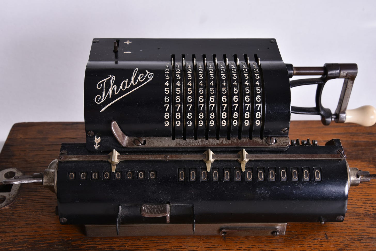 Photo of a simple calculating machine built in 1911. It is black with white writing and has nine rows of numbers.