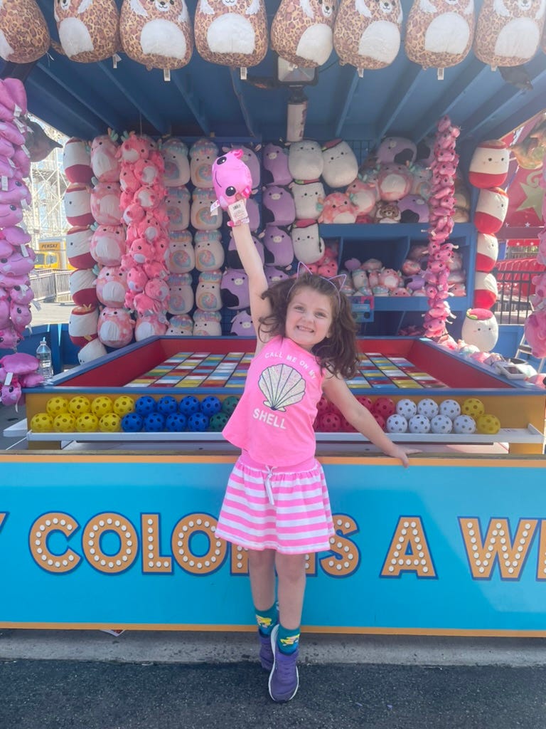 Little girl winning a stuffie on Coney Island arcade game