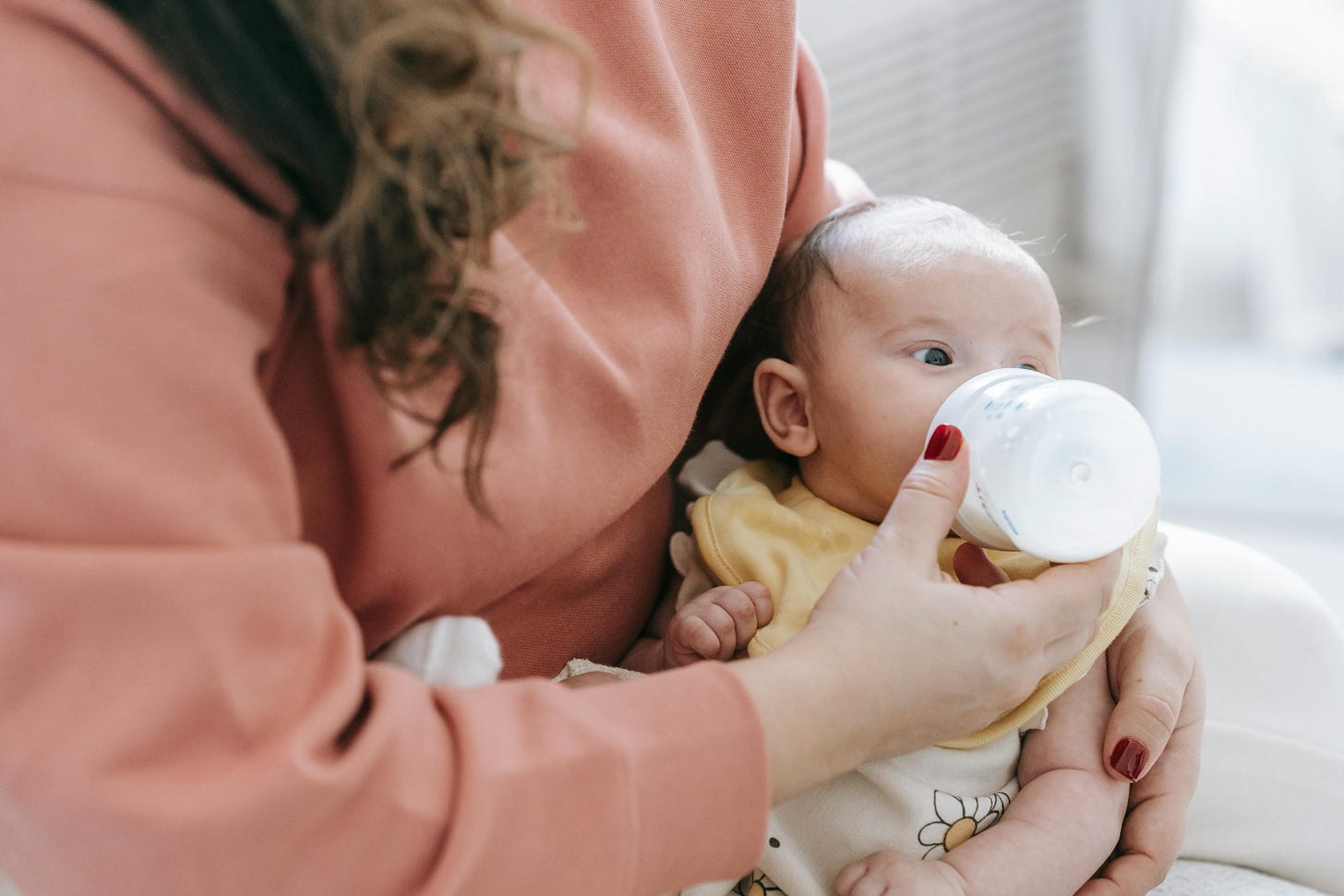 Unidentified woman giving baby a bottle Unidentified woman giving baby a bottle