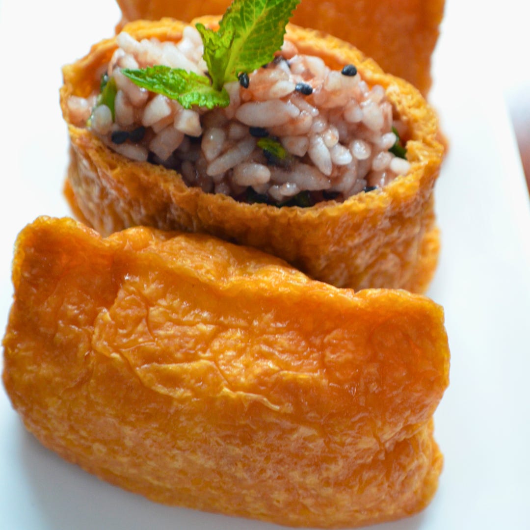 A close-up of inari sushi: sweet and savory tofu pouches filled with sushi rice.