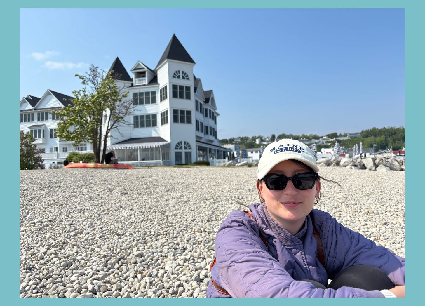 Photo of woman sitting on pebble beach with grand hotel in the background