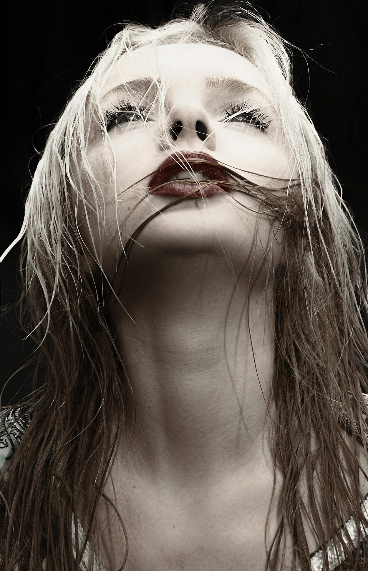 Portrait of a woman with blond hair and red lipstick. She’s looking up and has slightly parted lips. Portrait of a woman with blond hair and red lipstick. She’s looking up and has slightly parted lips.