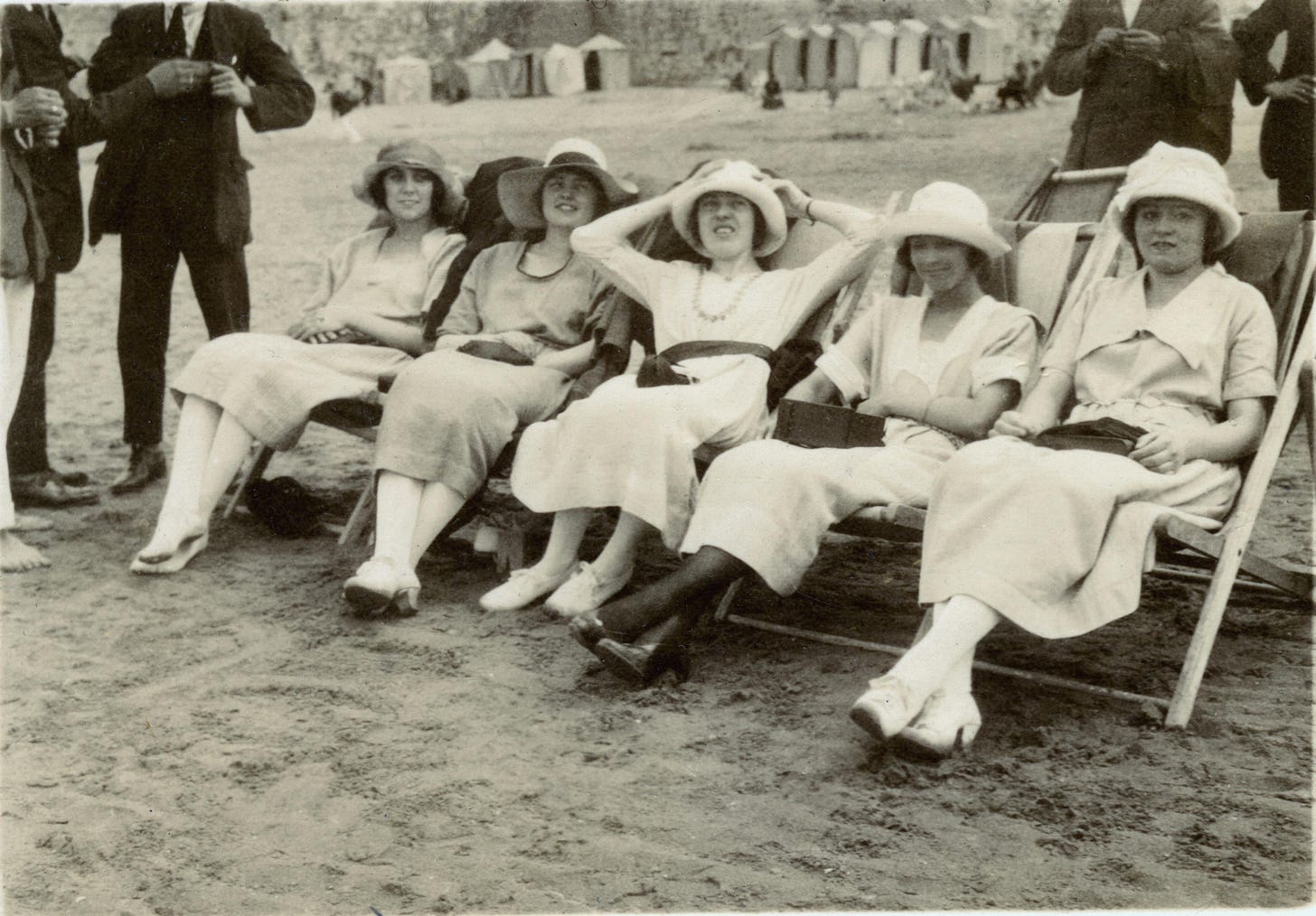 Vintage photo of a row of women sitting in chairs on a beach. Vintage photo of a row of women sitting in chairs on a beach.