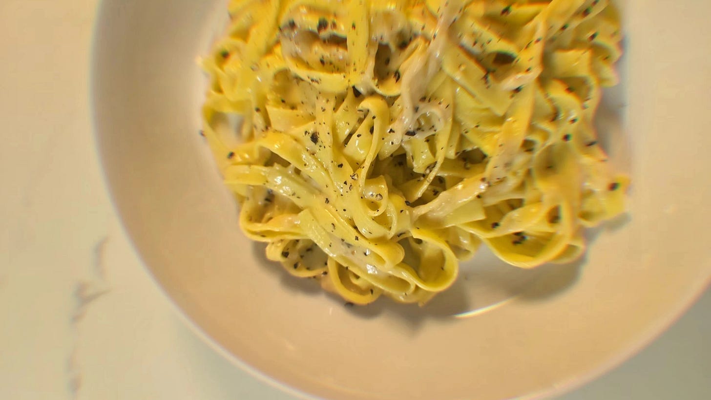 A white dish filled with fresh pasta (cacio e pepe made by Dr. Cadet) with black pepper and parmesan cheese sits on a white marble counter top. Photo: Dr. Cadet