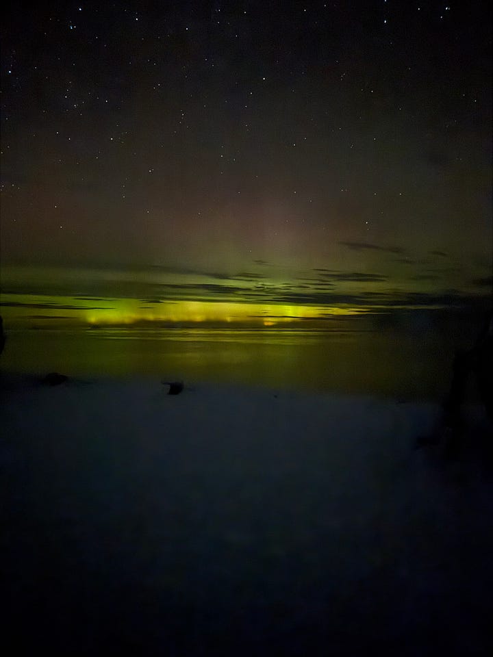 Images show the green haze of the Southern Lights over the sea.
