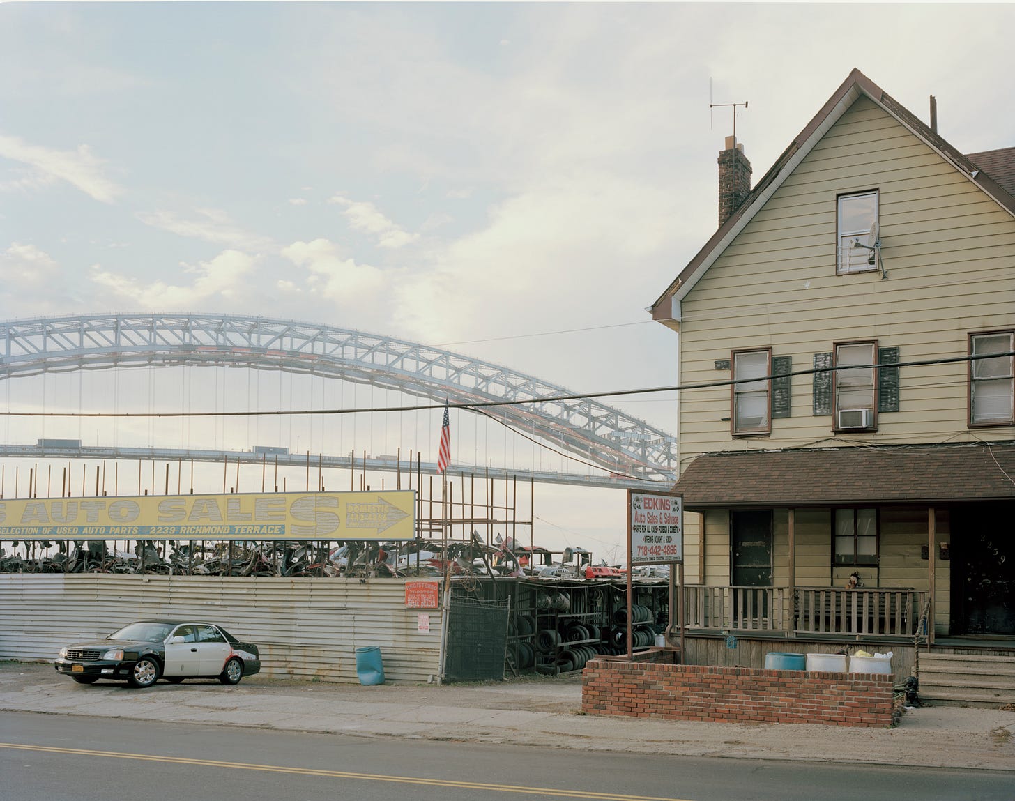 Salvage yard with yellow house and Bayonne Bridge in the distance