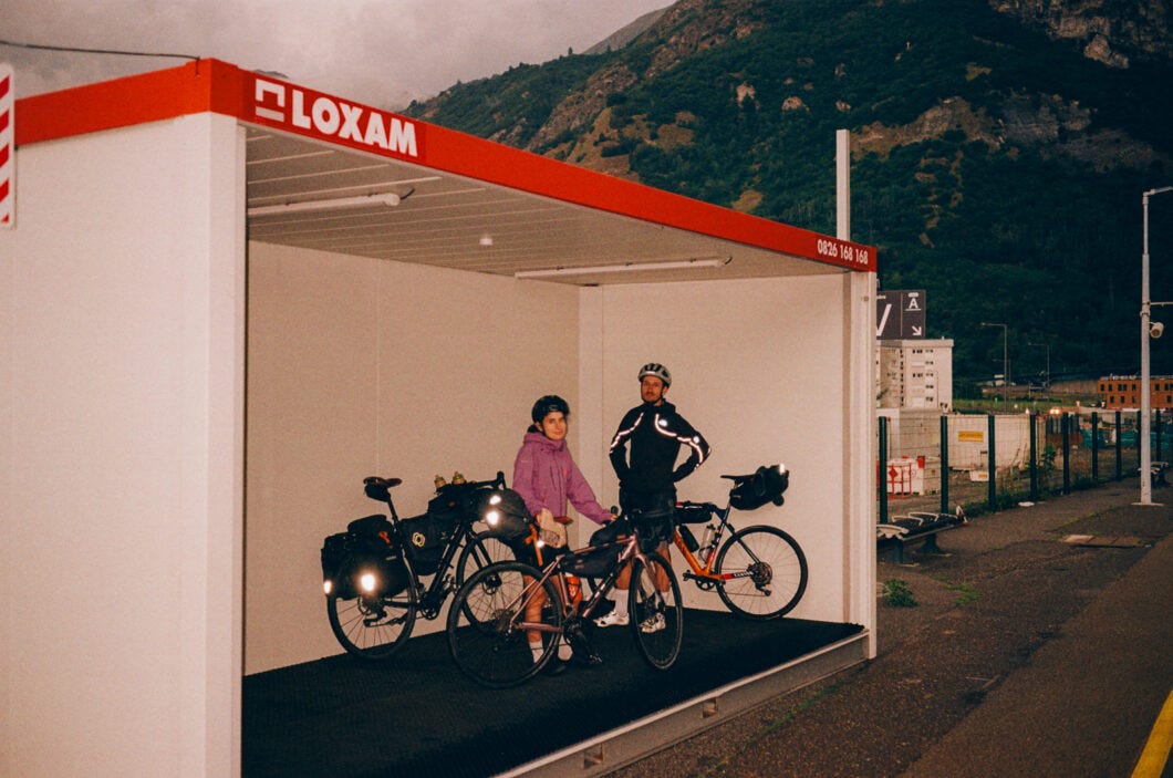 Couple attendant avec leur velo dans une algeco le long d'une route de montagne