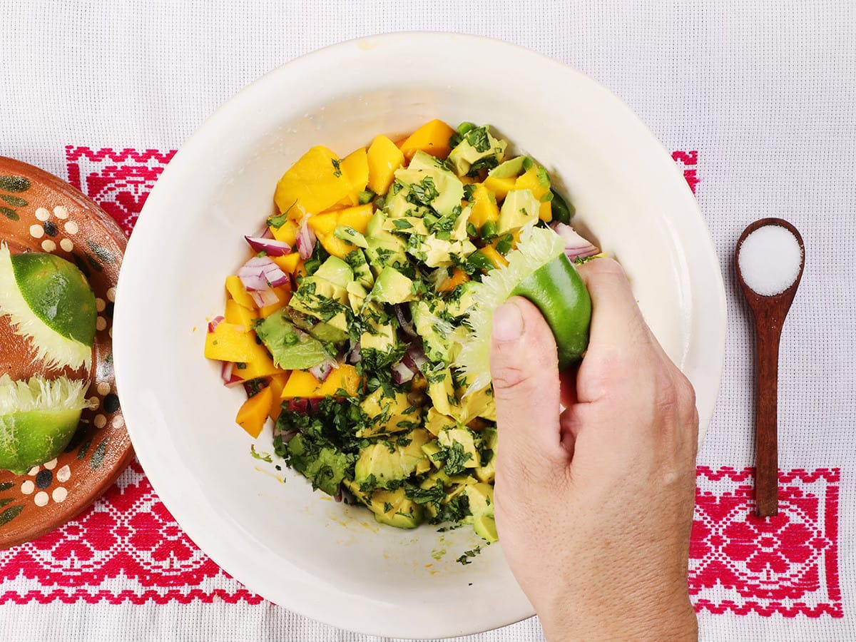 squeezing lime on mango avocado salsa