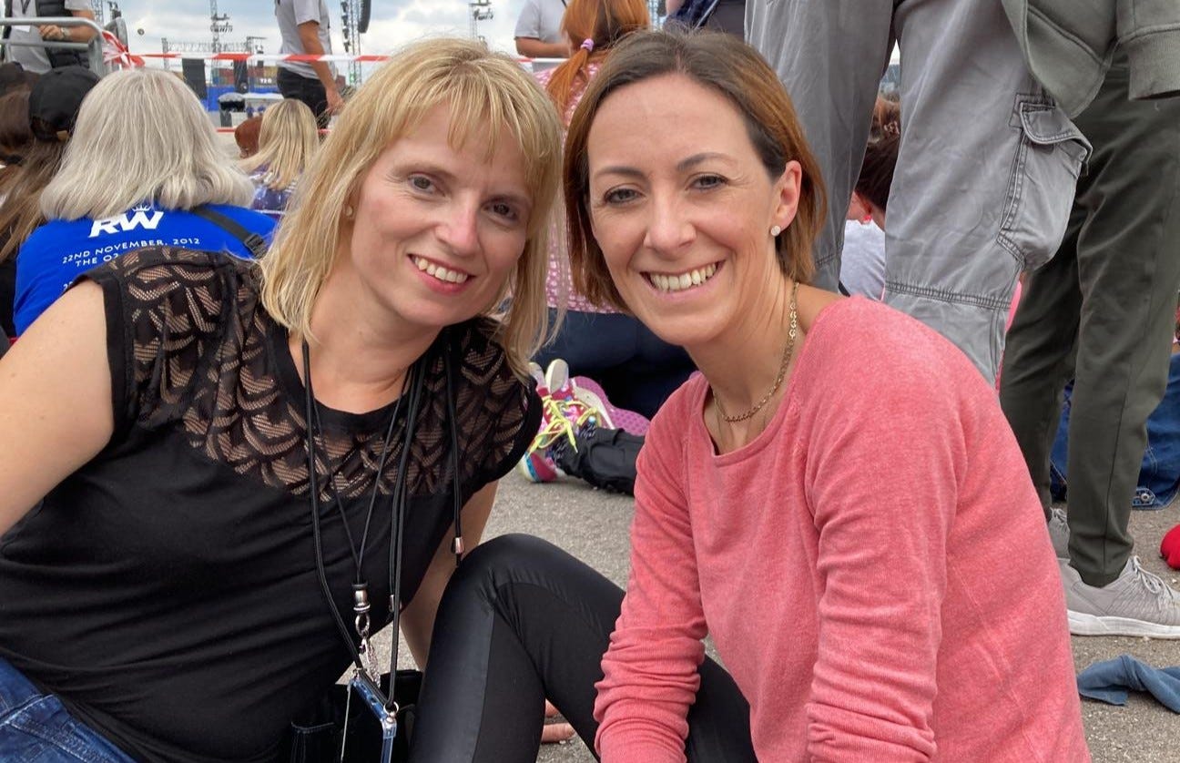 Zwei Freundinnen sitzen auf dem Boden und warten auf den Start des Konzerts.