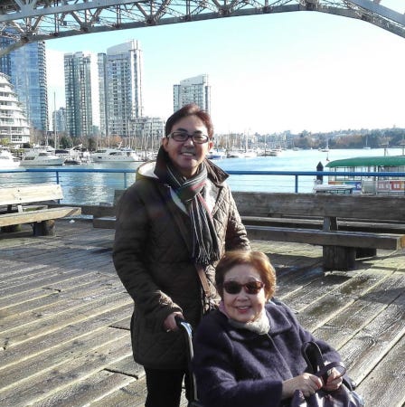 Kayoko Ebina, souriante, en fauteuil roulant sur une jetée de bord de mer