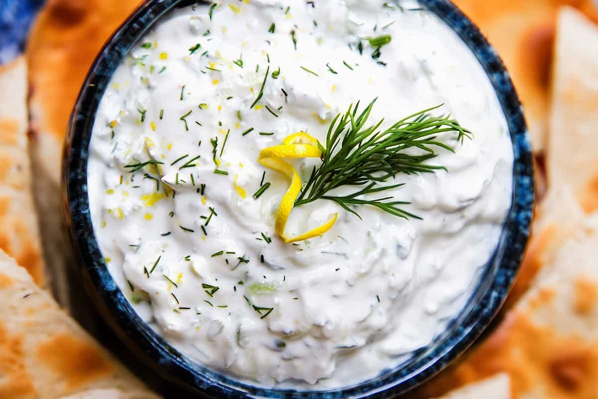 Creamy homemade tzatziki topped with fresh dill and lemon zest and served with pita bread.