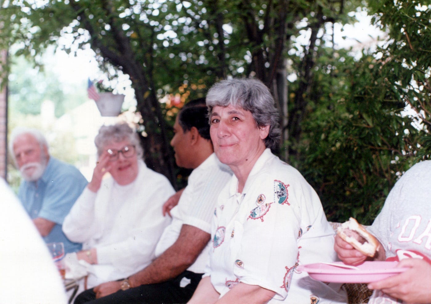 Photo of people at a barbecue. A woman in the center is smiling