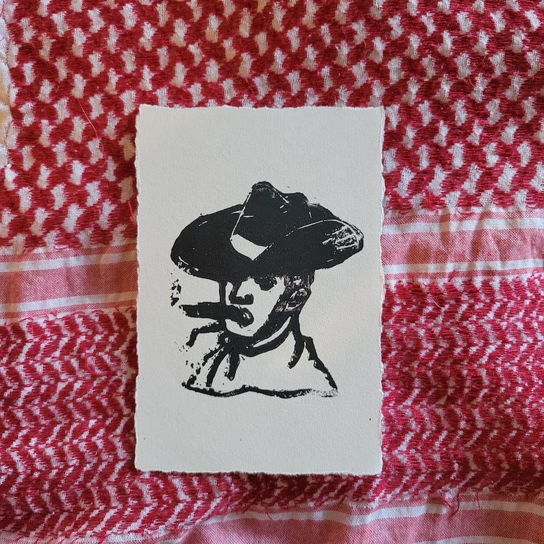 May include: A black and white print of a person wearing a cowboy hat and smoking a cigar. The print is on a piece of paper with a rough edge. The background is a red and white patterned cloth.