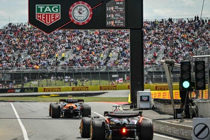 Race cars on a track with spectators in the background