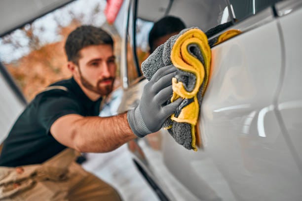 Man after washing wipes white car with a rag at car wash. Man after washing wipes white car with a rag at car wash. Selective focus. Car Detailing Services stock pictures, royalty-free photos & images