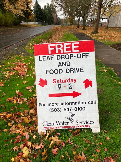 Subara hatch open with bags of leaves, food drive and leave drop-off sign, tractor lift