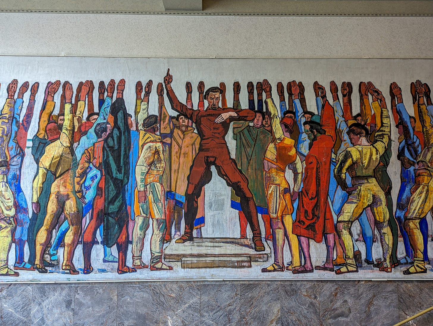 Mural showing a man standing with raised arm among a group of men cheering him on