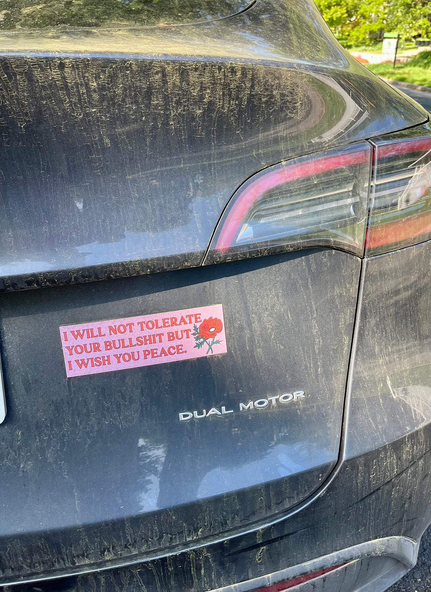 A car with a bumper sticker reading "I do not tolerate your bullshit, but I wish you peace."